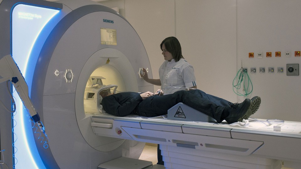 Medisch-specialistische zorg: Begeleidster naast patiënt in een MRI-scanner