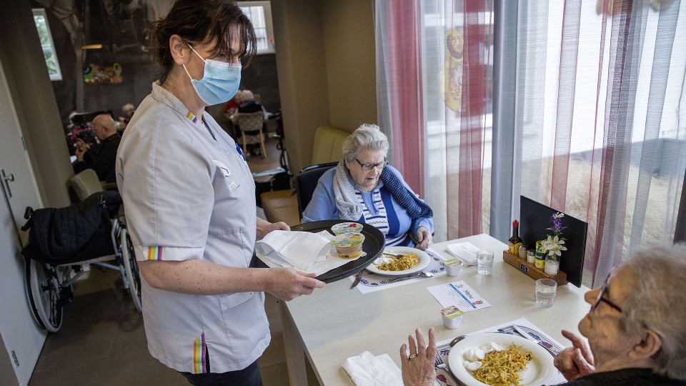 Verpleeghuiszorg: Verzorgende brengt eten rond bij cliënten