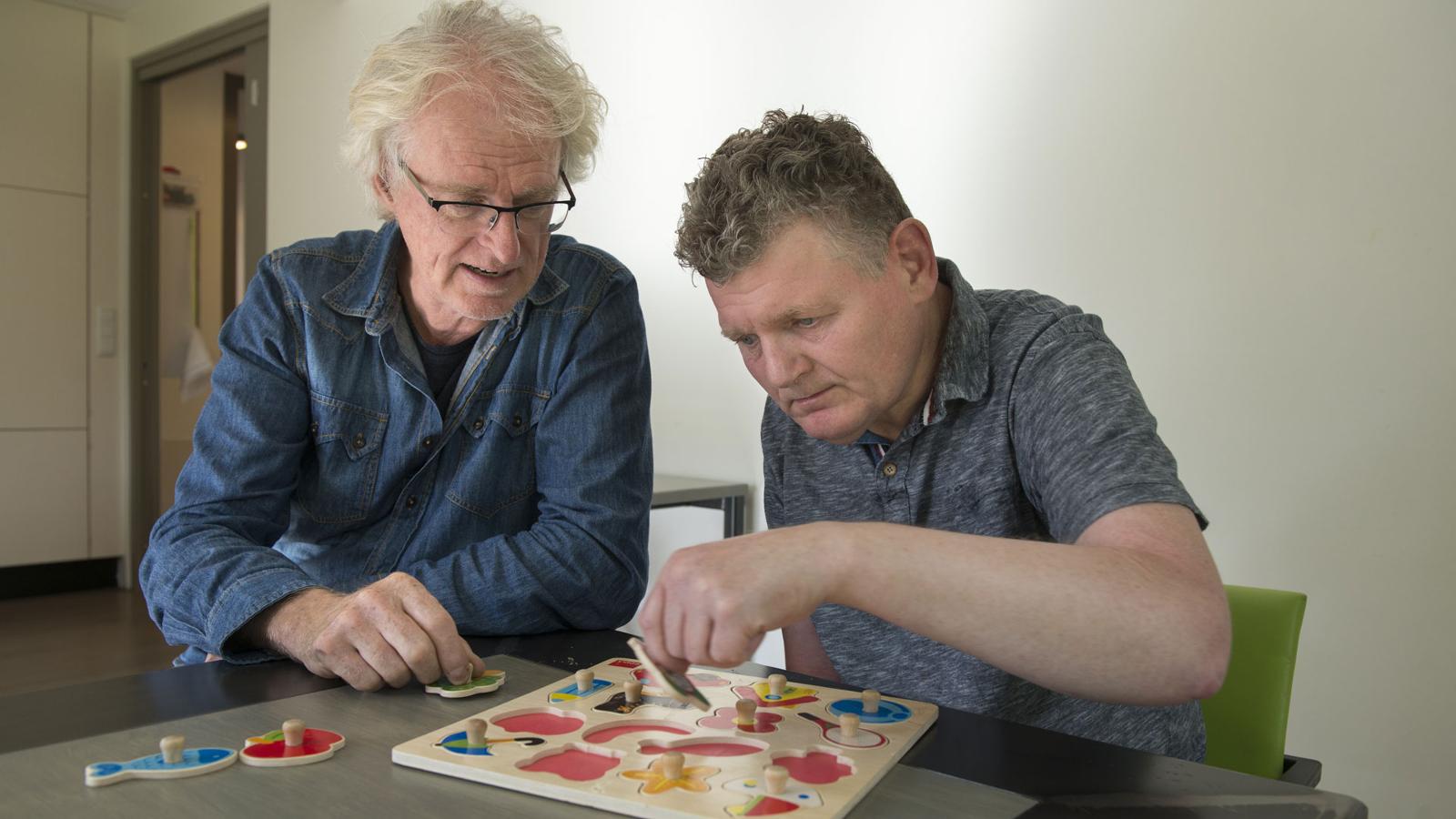 Geestelijke gezondheidszorg: begeleider helpt cliënt met puzzelen